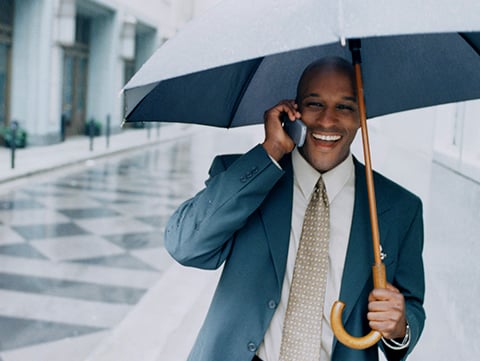 Man talking on cellphone holding open umbrella