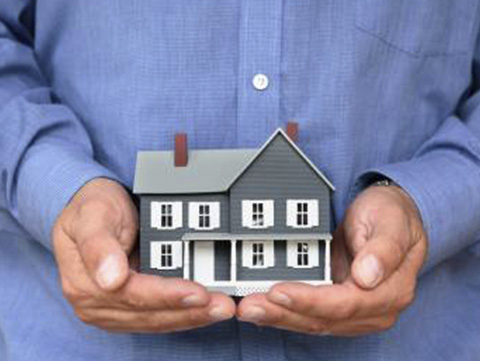 A person holding a replica of a home in their hands