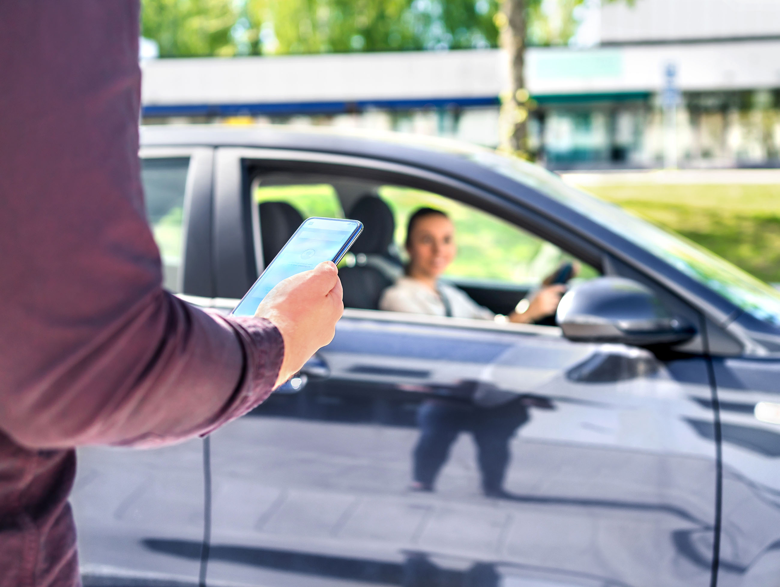 Person Holding Phone Near Rideshare Car