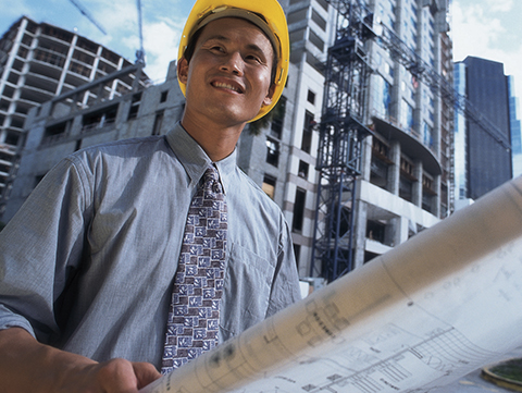 Female in hard hat on a job site looking at plans