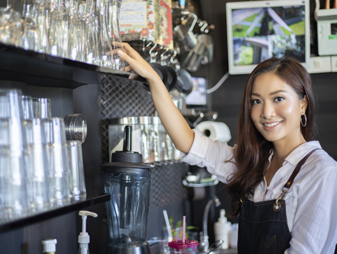 Asian female grabbing glass from shelf in restaurant