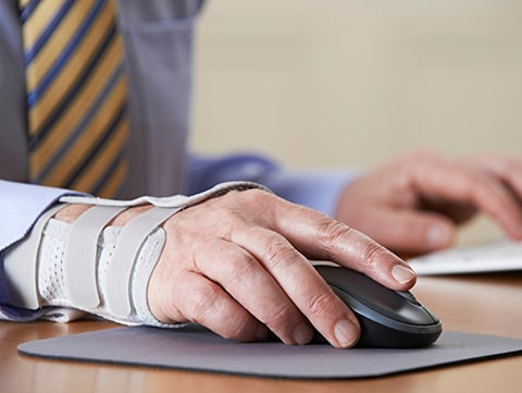 Close up of businessman with arm in a brace working at computer