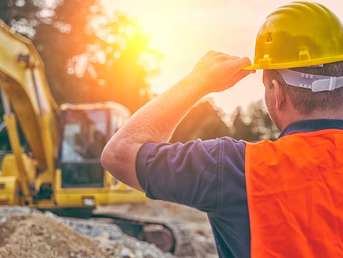 Construction worker on job site watching excavation